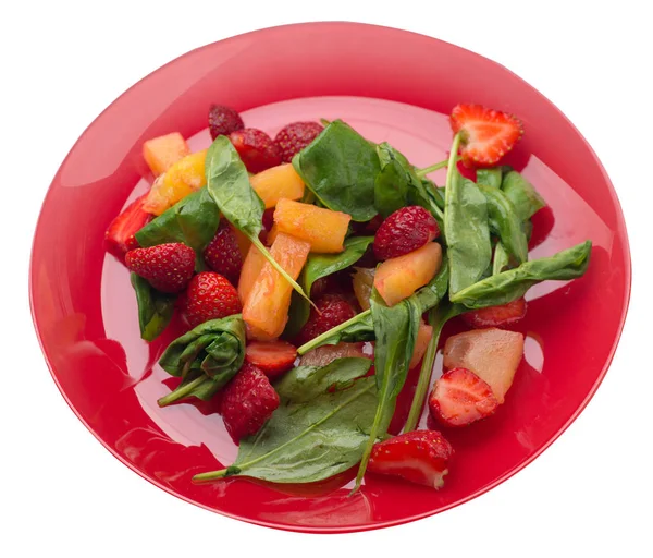 salad with strawberries, pineapple and spinach on a plate. frui