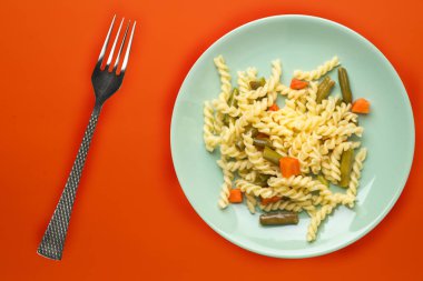 sebzeli ve titanyum kaplı bir tabakta makarna.