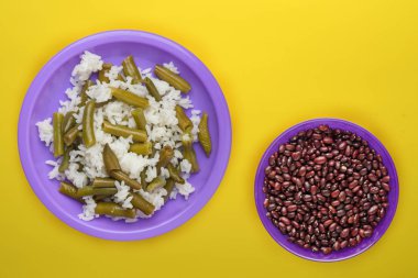 Sarı arka planda mor tabakta pirinç. Beyaz pirinç üstü vi