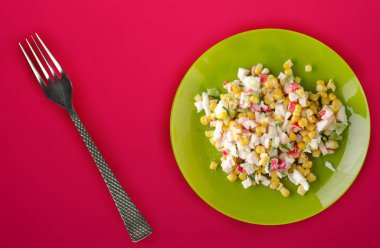  Yeşil tabakta yengeç salatası. Kırmızı arka planda yengeç salatası