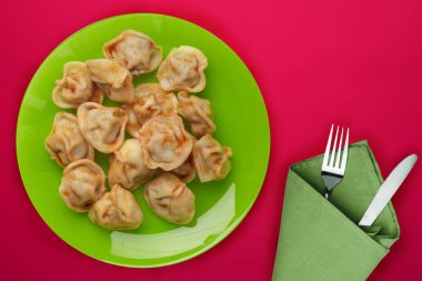 Kırmızı arka planda yeşil tabakta hamur köftesi. Hamur tatlısı.