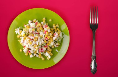  Yeşil tabakta yengeç salatası. Kırmızı arka planda yengeç salatası