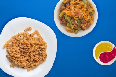 Domates soslu beyaz tabakta makarna ve sebze salatası.