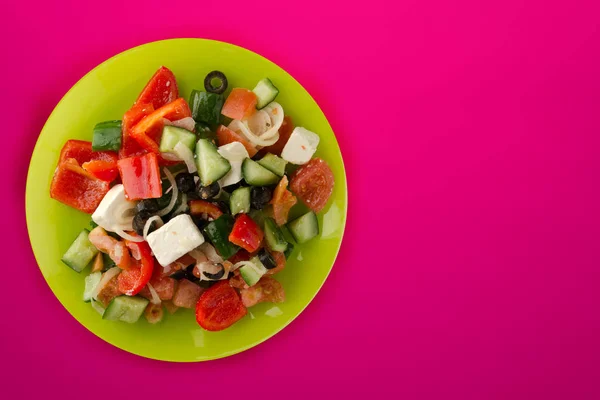 Griechischer Salat auf rotem Hintergrund. griechischer Salat auf grünem Teller — Stockfoto