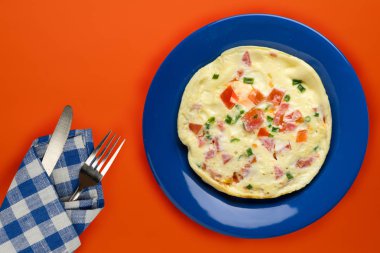 Turuncu arka planda mavi bir tabakta omlet. sağlıklı kahvaltılıklar