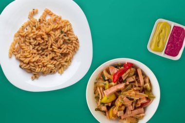 Domates soslu beyaz tabakta makarna ve sebze salatası.