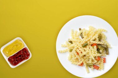 Renkli arka planda sebzeli bir tabakta makarna. Ortam