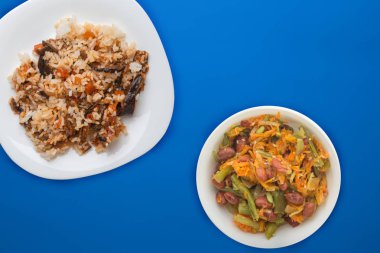  Beyaz tabakta pilav ve renkli bir sırt üzerinde sebze salatası.