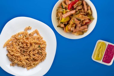 Domates soslu beyaz tabakta makarna ve sebze salatası.