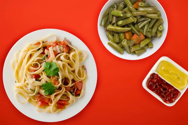 Espaguetis en un plato blanco. espaguetis tomates, cebollas, col —  Fotos de Stock