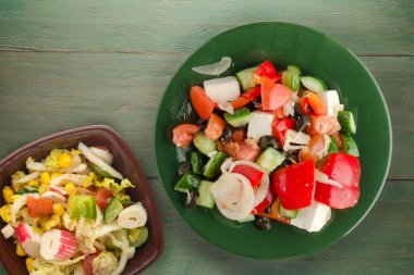 Yeşil ahşap arka planda Yunan salatası. Vejetaryen salata manzaralı yeşil tabakta Yunan salatası. sağlıklı yiyecekler