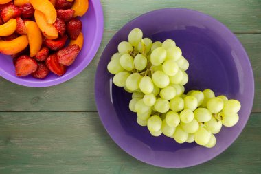 Yeşil ahşap arka planda üzümler. Mor plaka manzaralı üzümler. sağlıklı yiyecekler
