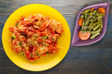 Mavi ahşap arka planda sarı tabakta soğanlı haşlanmış domates. vejetaryen yemeği