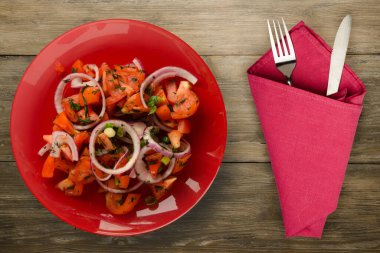 Çatal ve bıçak manzaralı vejetaryen yemekleri. Domates, soğan, kırmızı tabakta rezene kahverengi ahşap arka planda. sağlıklı yiyecekler