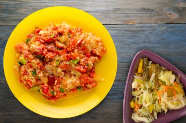 Mavi ahşap arka planda sarı tabakta soğanlı haşlanmış domates. vejetaryen yemeği