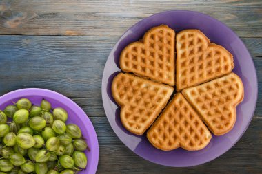 Belçika waffle 'ı mavi ahşap arka plan. Mor bir tabakta meyveli waffle.