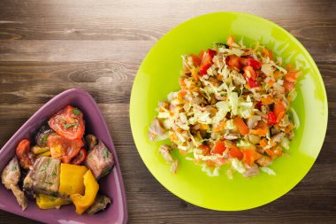 Tavuk mideli salata ile sebze havuç, soğan, biber, lahana, domates, brokoli. Kireç tabağında tavuk ve kahverengi ahşap arka planda salata. sağlıklı salatalar üst görünüm