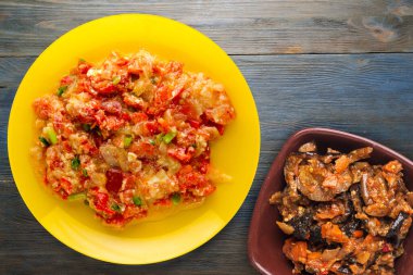 Mavi ahşap arka planda sarı tabakta soğanlı haşlanmış domates. vejetaryen yemeği