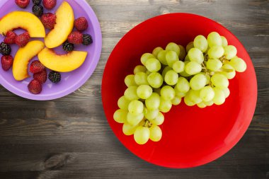 Siyah ahşap arka planda üzümler. Kırmızı tabakta üzümler. Sağlıklı vejetaryen yemekleri.
