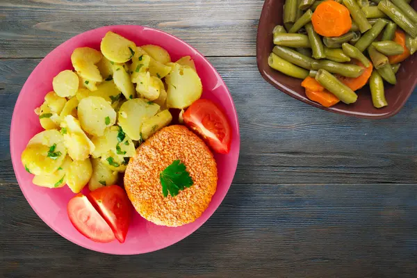肉丸子 灰色蓝色木制背景的土豆 肉丸子 粉红色盘子里有一片西红柿 上面有蔬菜沙拉 — 图库照片