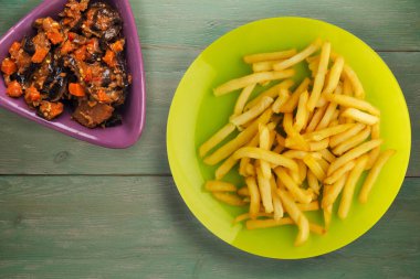 Patatesleri yeşil ahşap arka planda kızart. Limonlu patates kızartması ve sebze salatası.