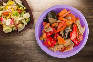 Kahverengi ahşap arka planda sebze güveci. Mor tabakta Bulgar güveci ve vejetaryen salata üstü manzarası