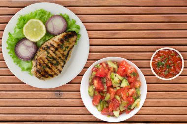 Sebzeli ızgara tavuk fileto limon, salata, portakal ağacından arka planda soğan. Tavuklu fileto, beyaz tabak şeklinde ızgara.