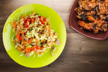 Tavuk mideli salata ile sebze havuç, soğan, biber, lahana, domates, brokoli. Kireç tabağında tavuk ve kahverengi ahşap arka planda salata. sağlıklı salatalar üst görünüm