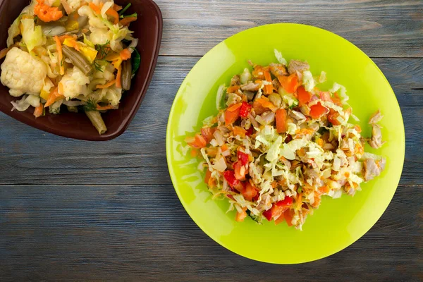 salad with chicken stomachs with vegetables carrots, onions, peppers, cabbage, tomato, broccoli. salad with chicken on yellow plate on blue wooden background.vegetarian food top view
