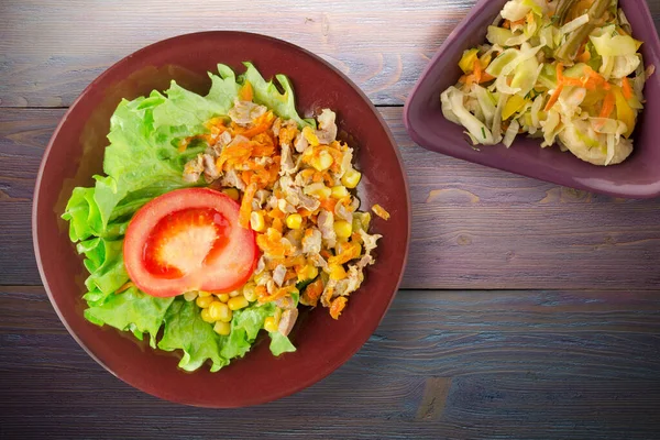 salad with chicken stomachs with carrots and corn and salad on brown plate with vegetable salad top view. chicken salad with vegetables on purple wooden background