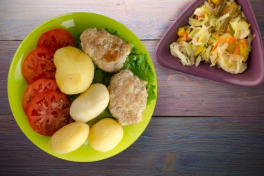 Limonlu patatesli pirzola ve sebze salatası. Patatesli pirzola ve mor ahşap arka plan.