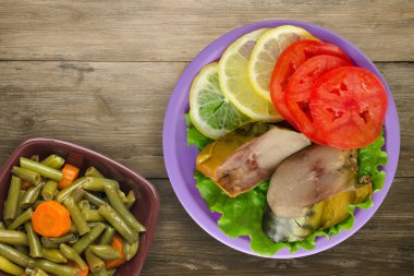 Mor tabakta tütsülenmiş uskumru. Sebze salatası manzaralı. Kahverengi ahşap arka planda limonlu uskumru ve domates.