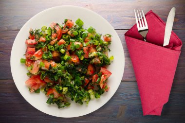 Çatal ve bıçak manzaralı vejetaryen yemekleri. Domates, soğan, beyaz tabakta rezene mor ahşap arka planda. sağlıklı yiyecekler