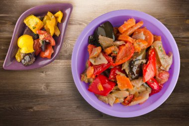 Kahverengi ahşap arka planda sebze güveci. Mor tabakta Bulgar güveci ve vejetaryen salata üstü manzarası