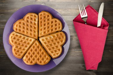Siyah ahşap arka planda çatal ve bıçaklı Belçika waffleları. Mor bir tabakta waffle.
