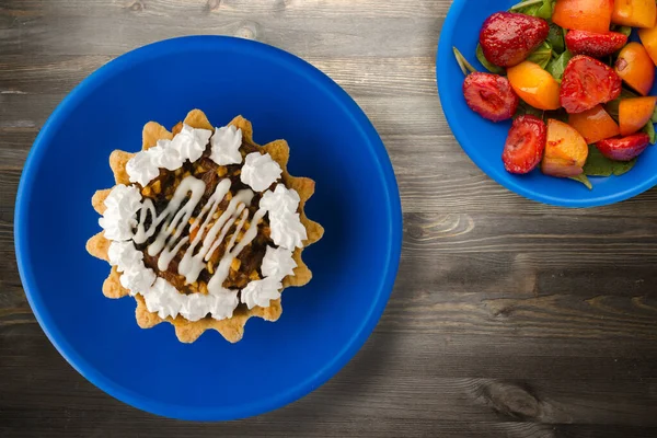 cake on a black wooden background. cake on a blue plate with fruits top view