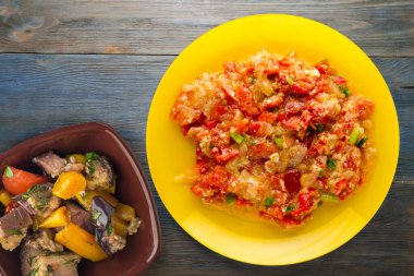 Mavi ahşap arka planda sarı tabakta soğanlı haşlanmış domates. vejetaryen yemeği