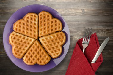 Siyah ahşap arka planda çatal ve bıçaklı Belçika waffleları. Mor bir tabakta waffle.