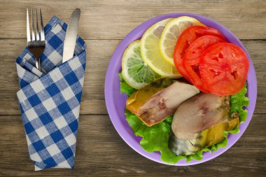 Mor tabakta füme uskumru. Çatal ve bıçak manzaralı. Kahverengi ahşap arka planda limonlu uskumru ve domates.