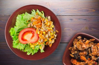 Havuçlu tavuk mideli salata, mısır ve sebze salatası manzaralı kahverengi tabakta salata. Mor ahşap arka planda sebzeli tavuk salatası