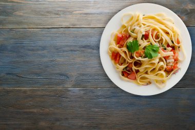 Vejetaryen salata manzaralı beyaz tabakta spagetti. domatesler, soğanlar, lahanalar mavi ahşap arka planda