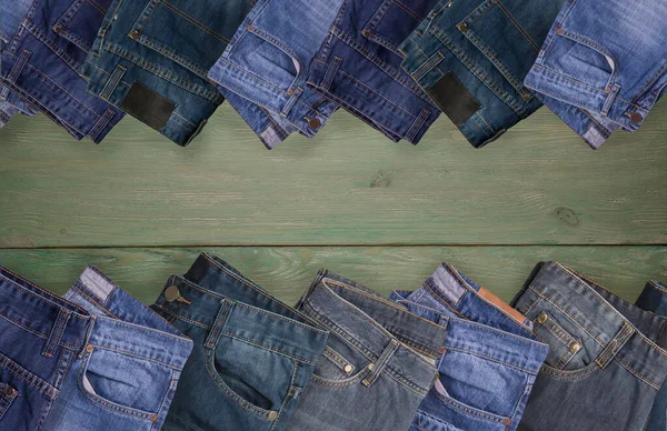 Jeans folded on green wooden background, Top view with copy work space.