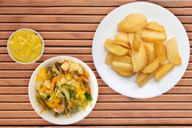 Turuncu ahşap arka planda sebze salatalı patates kızartması. Patatesleri beyaz tabakta kızart