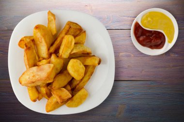 Patatesleri mor ahşap arka planda kızart. Soslu, beyaz tabakta patates kızartması.