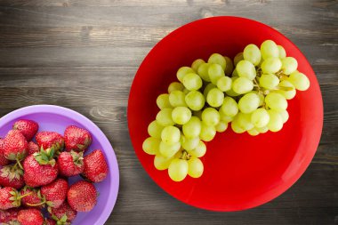 Siyah ahşap arka planda üzümler. Kırmızı tabakta üzümler. Sağlıklı vejetaryen yemekleri.