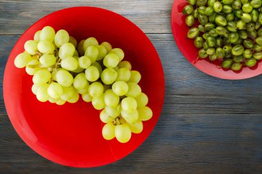 Mavi ahşap arka planda üzümler. Meyve salatası manzaralı kırmızı bir tabakta üzümler