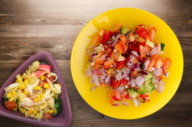 Vejetaryen yemeği. Biberli salata, domates, soğan, sarı tabakta sebze salatası manzaralı brokoli. Kahverengi ahşap arka planda vegan salatası