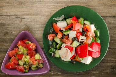 Kahverengi ahşap arka planda Yunan salatası. Vejetaryen salata manzaralı yeşil tabakta Yunan salatası. sağlıklı yiyecekler