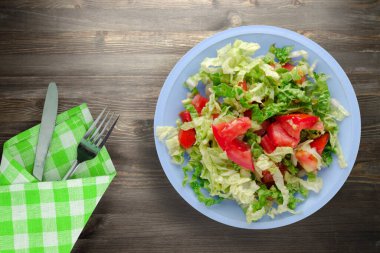 Çatal ve bıçak manzaralı vejetaryen yemekleri. Siyah ahşap arka planda lahanalı domates salatası. sağlıklı yiyecekler