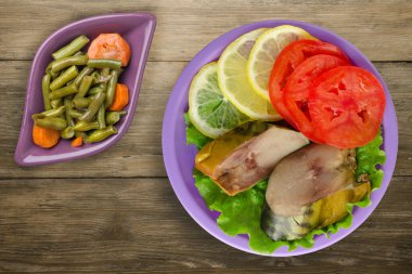 Mor tabakta tütsülenmiş uskumru. Sebze salatası manzaralı. Kahverengi ahşap arka planda limonlu uskumru ve domates.